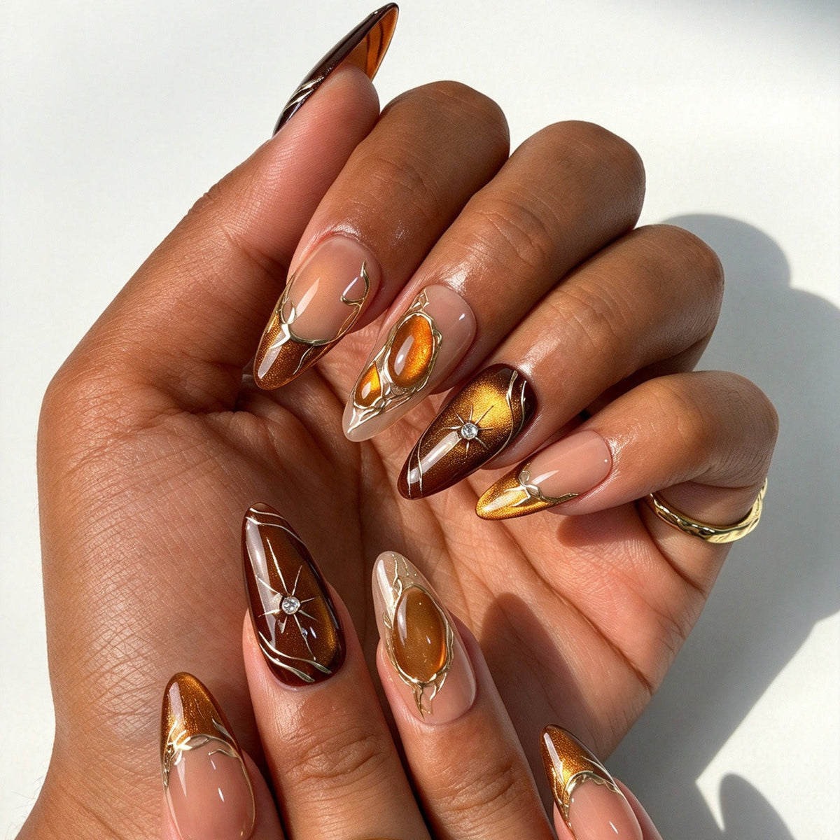 Closeup of Amber Star almond press on nails, amber cat eye, gold cracked line and star rhinestone decor