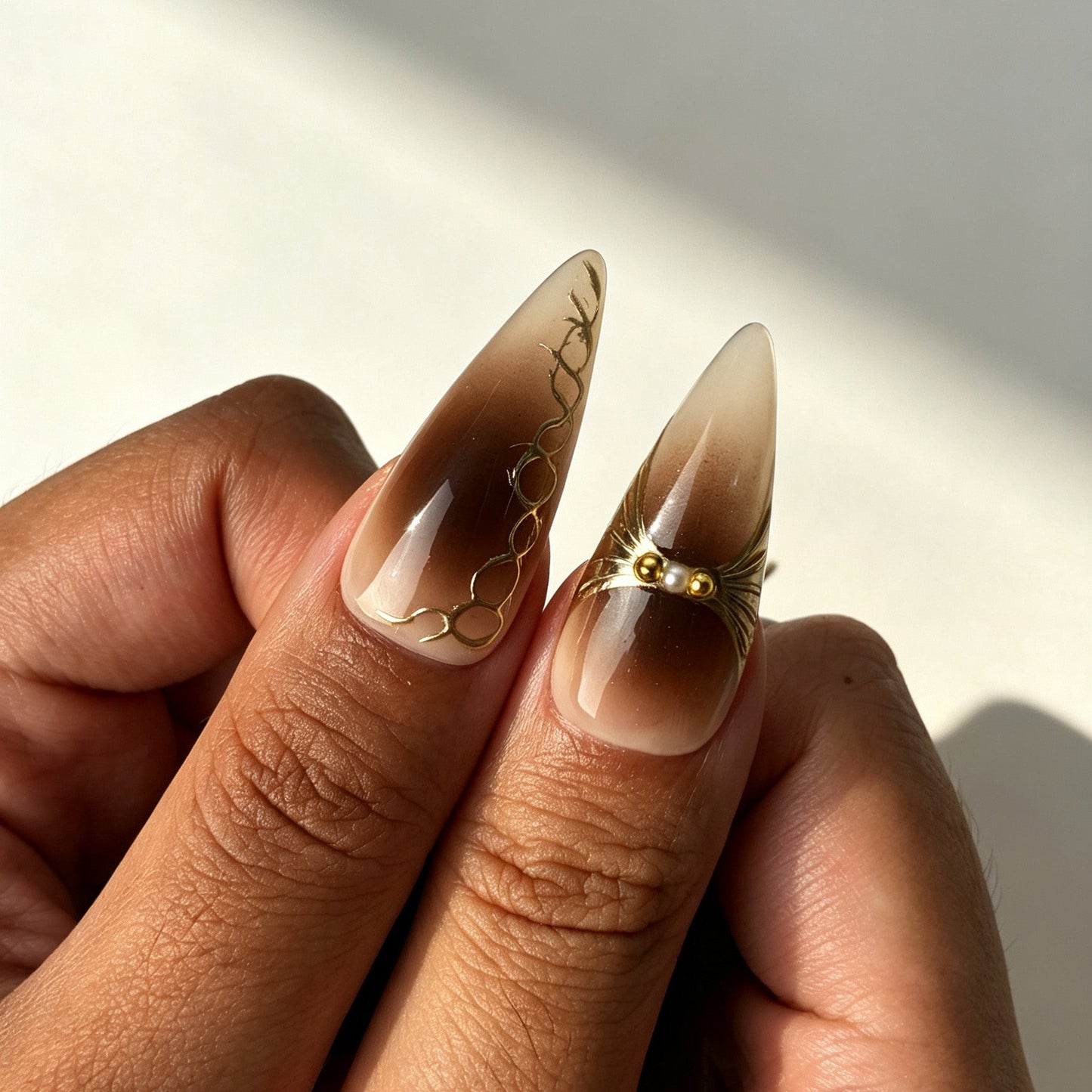 Coffee‑brown gold gradient stiletto press‑on nails with leopard print worn on fingernails