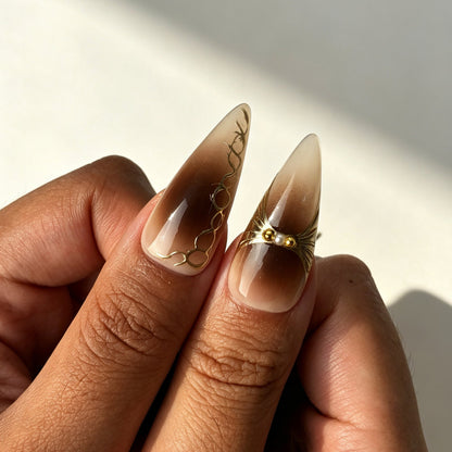 Coffee‑brown gold gradient stiletto press‑on nails with leopard print worn on fingernails