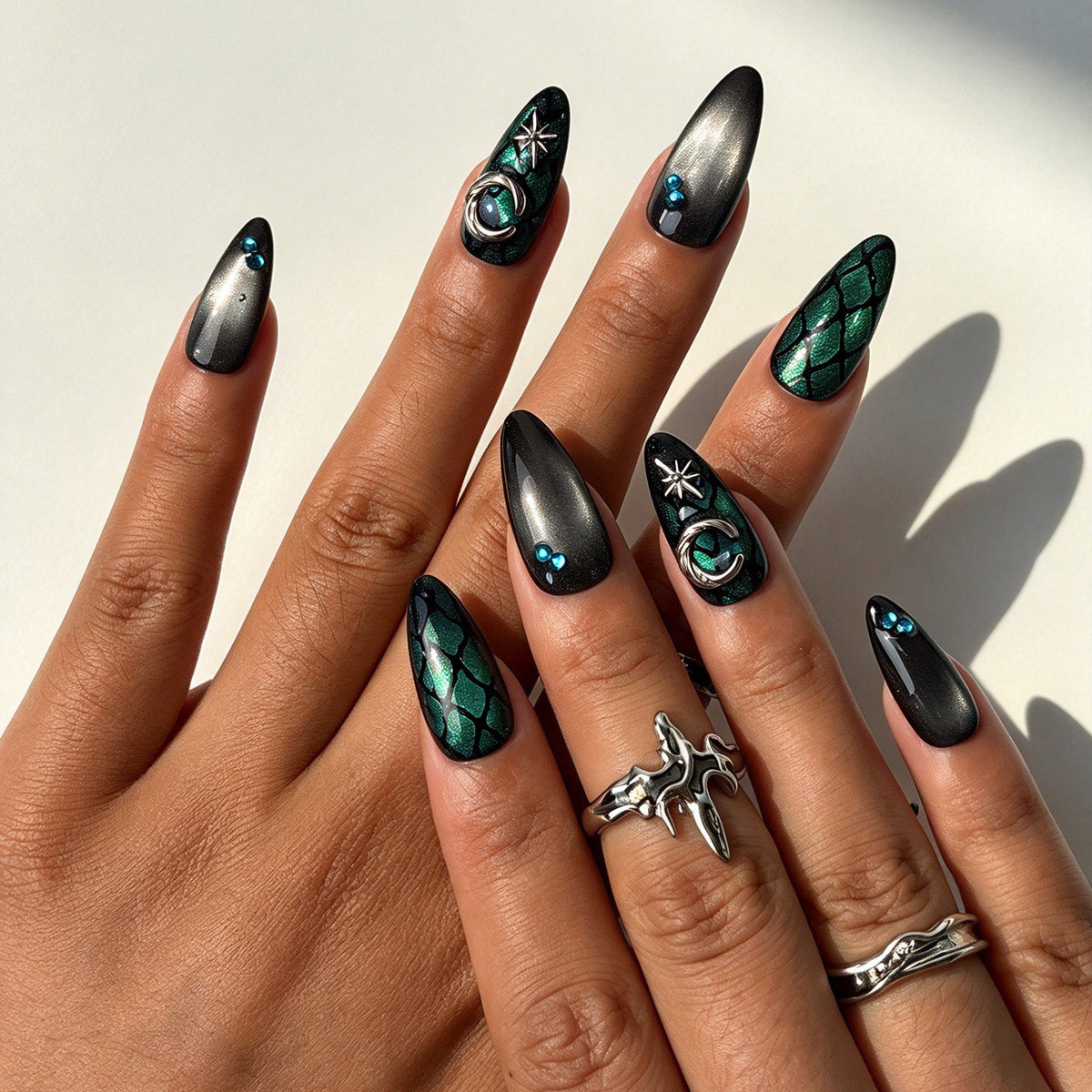 Closeup of hand with teal blue cat eye angel wing fake nails