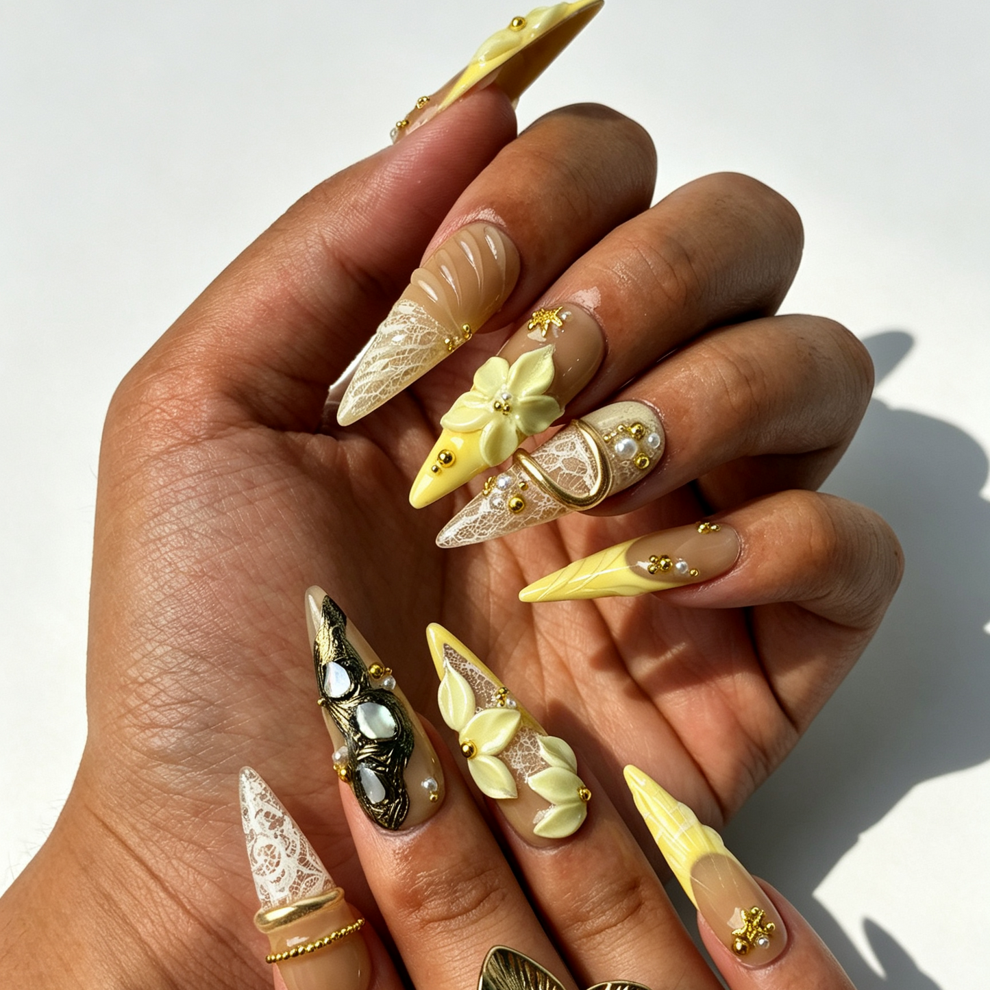 Cream Bloom soft long stiletto false nails close-up, sculpted ivory floral and layered gold line office manicure