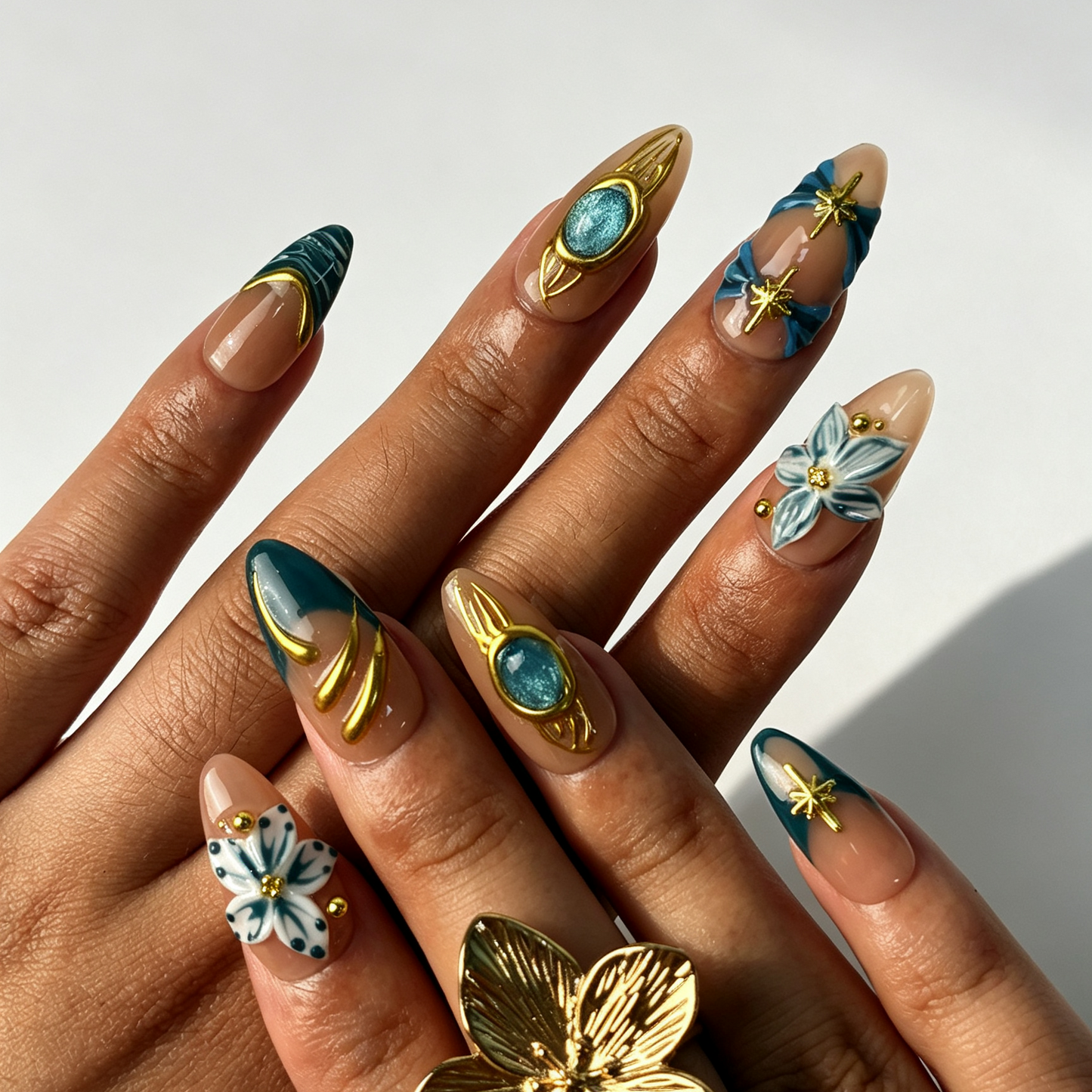 Jade Filigree nude almond false nails close-up, shimmer aqua cat eye with 3D blue flower, gold star and metal filigree decorations