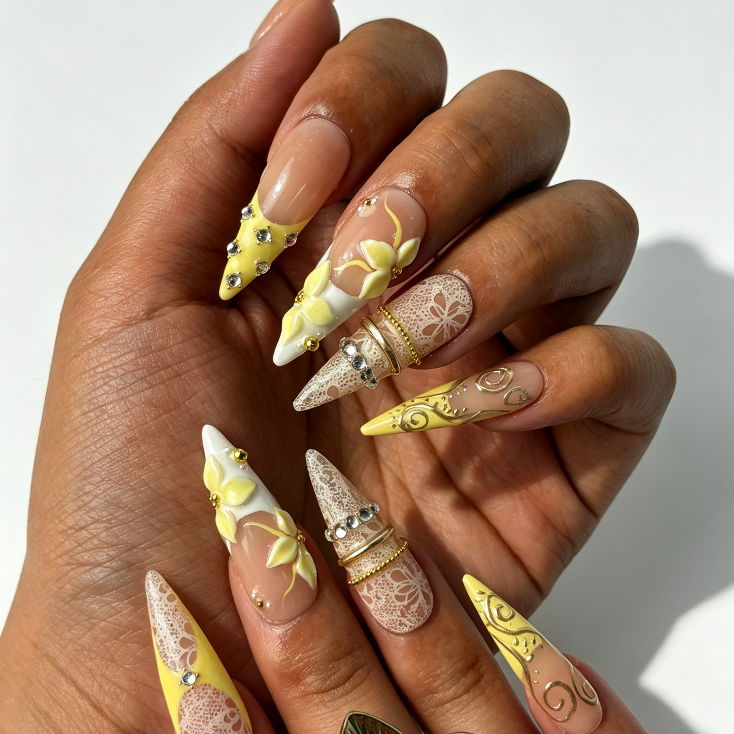 Lemon Lace long stiletto press on nails worn on hand, nude yellow french tip, lace print, pale yellow flower and silver swirl spring nail art