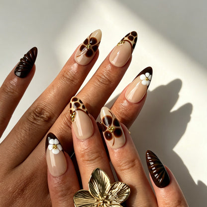Maillard almond false nails, sheer nude base, caramel leopard French tips, hand-painted florals and 3D white flowers
