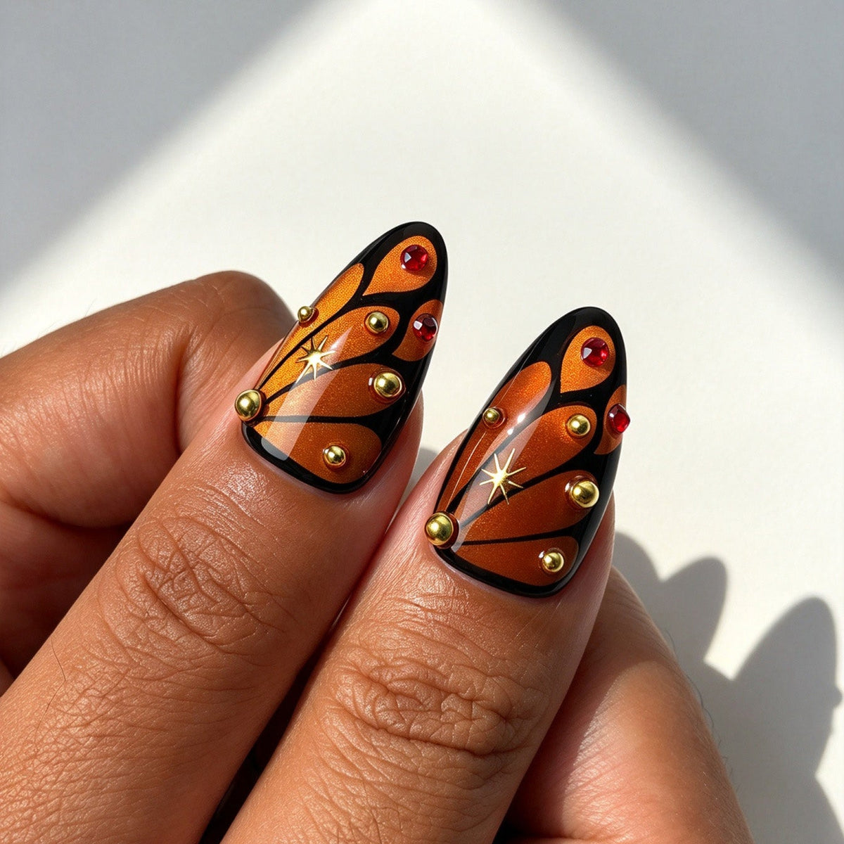 Closeup of Crimson Nocturne almond press on nails, butterfly wing, moon bat silhouette and gold starburst decor