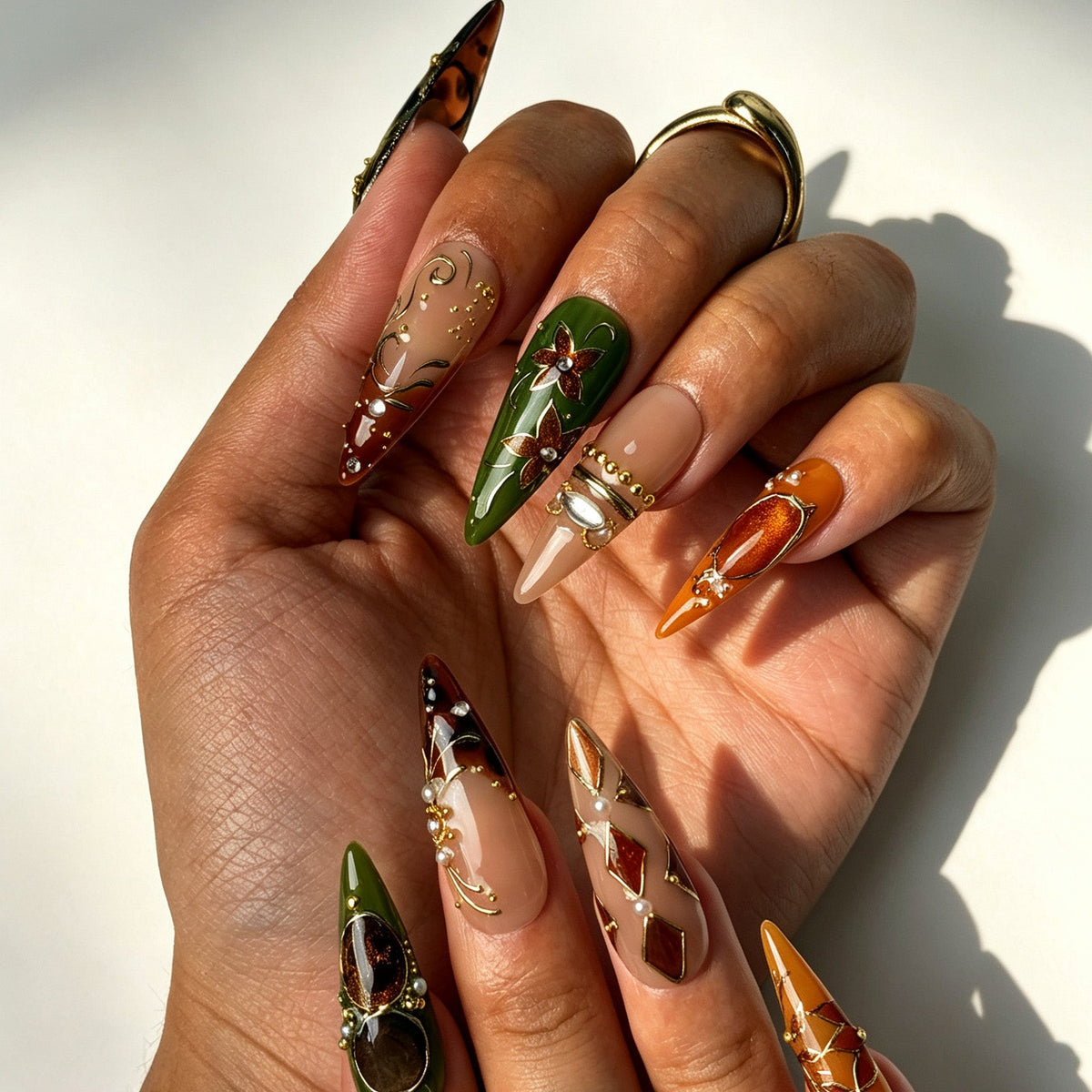 Boho-jeweled stiletto false nails, olive green orange nude palette, tortoiseshell gem, brown flower and crystal details