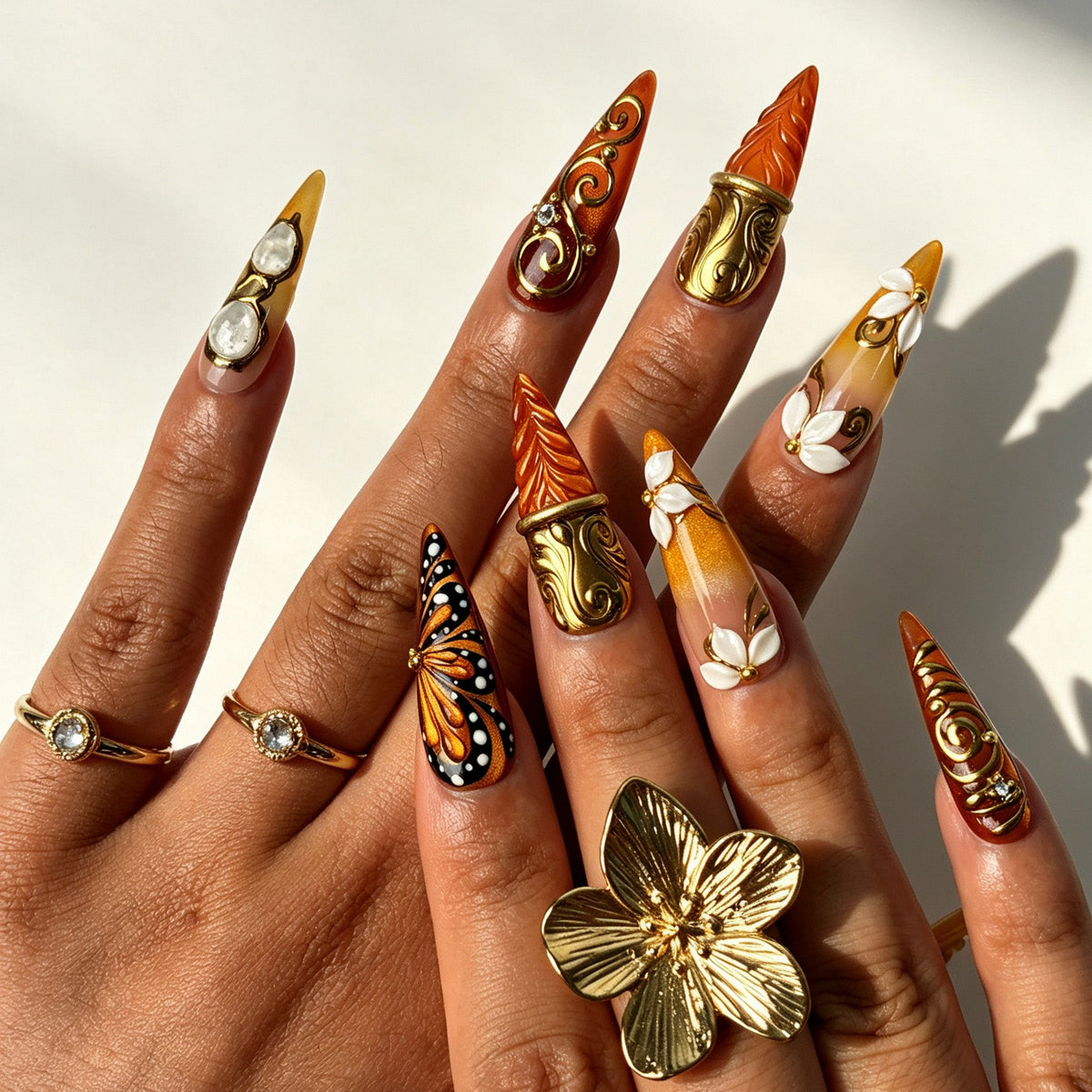 Model hand wearing Gilded Ember baroque stiletto press‑on nails with gold scroll decor