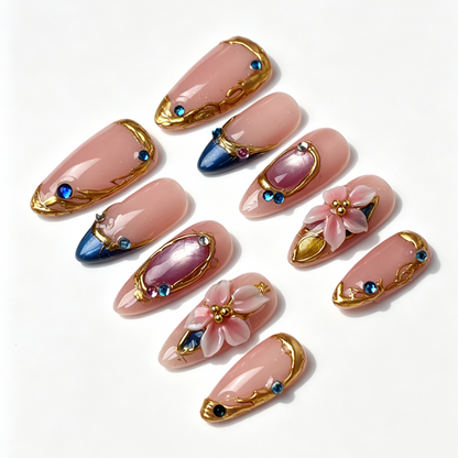 Teal Gilded spring fake nail set, nude base with teal cat eye french tip, sculpted pink floral, textured gilded border and round rhinestone embellishments