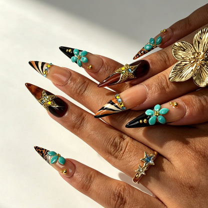 Close‑up hand shot of long stiletto false nails, teal flower and zebra‑leopard print