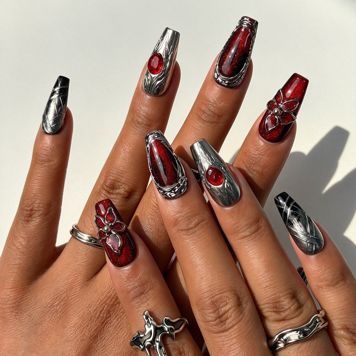 Closeup of hand with silver cracked burgundy 3D flower fake nails