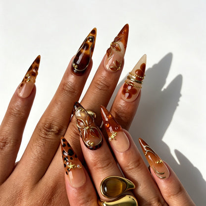 Luxury stiletto false nails, nude amber gradient, champagne glitter, tortoiseshell, gold chain and brown leaf details