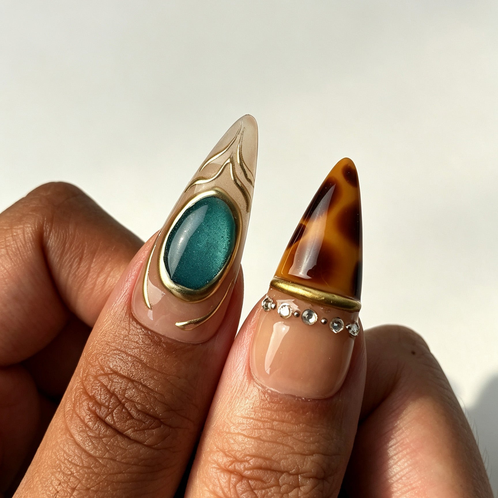 Model hand with long stiletto press‑on nails, turquoise gem & tortoise nail art
