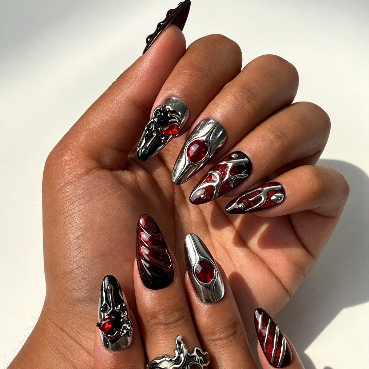 Closeup of hand with black red shimmer vampire style fake nails